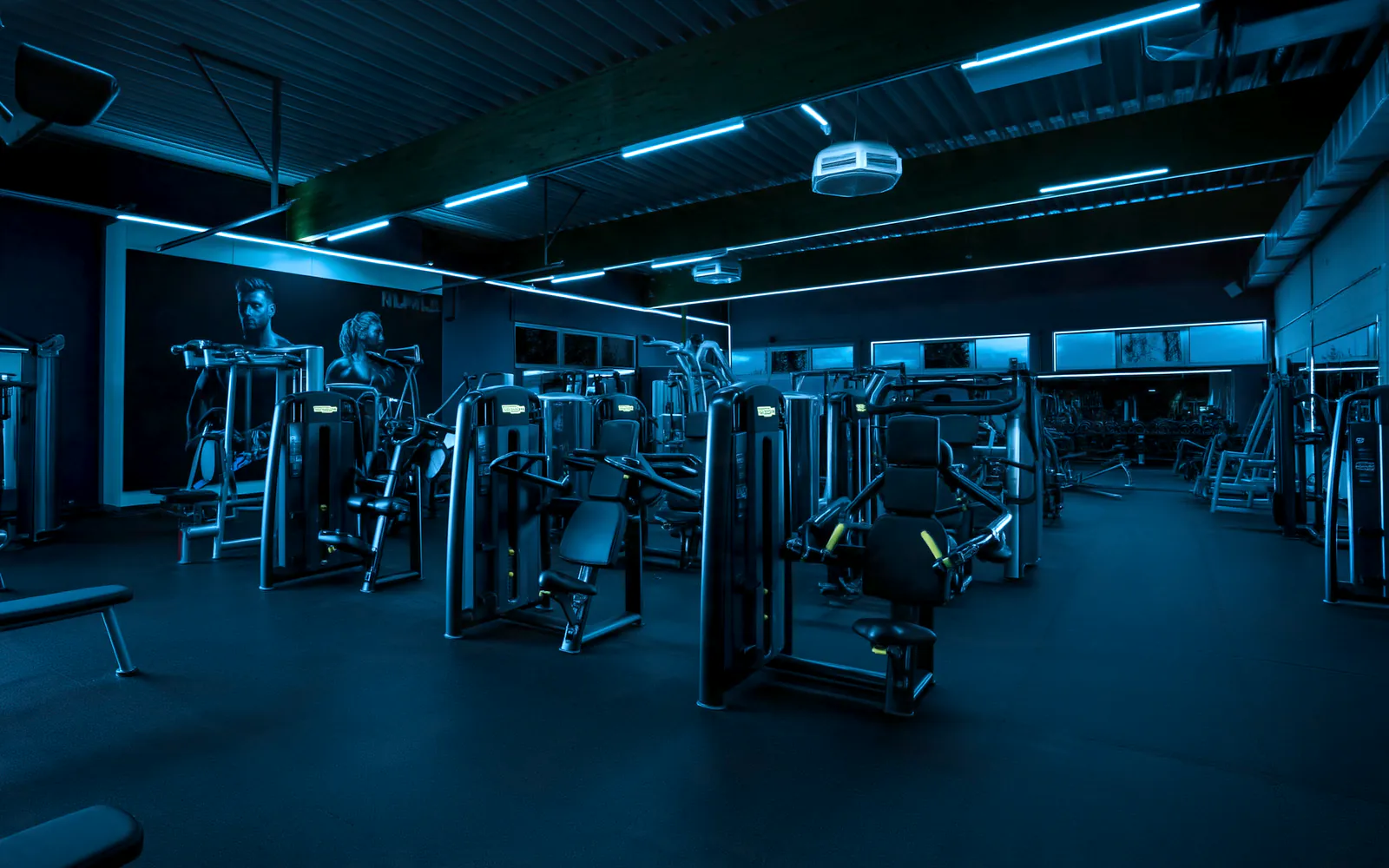 Die große Trainingshalle von Ruhl Fit 24 mit Geräten unter Holzbalken